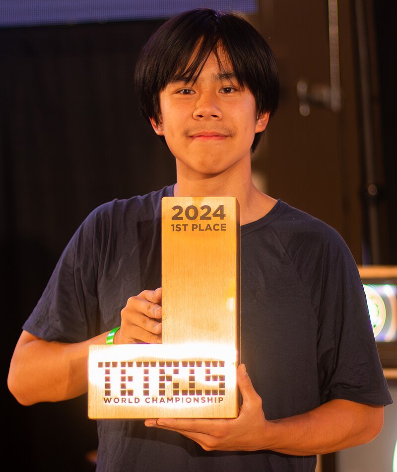 Thach in a black shirt holding a golden J-Piece trophy